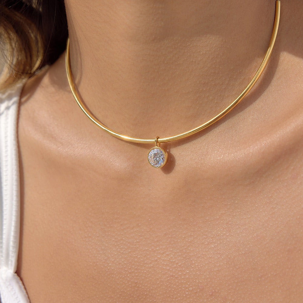 Gold aurea sol choker necklace with a round cubic zirconia pendant on a person's neck