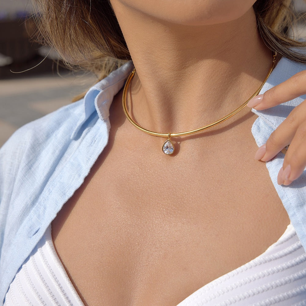 Gold aurea sol choker necklace with a pear cubic zirconia pendant on a person's neck
