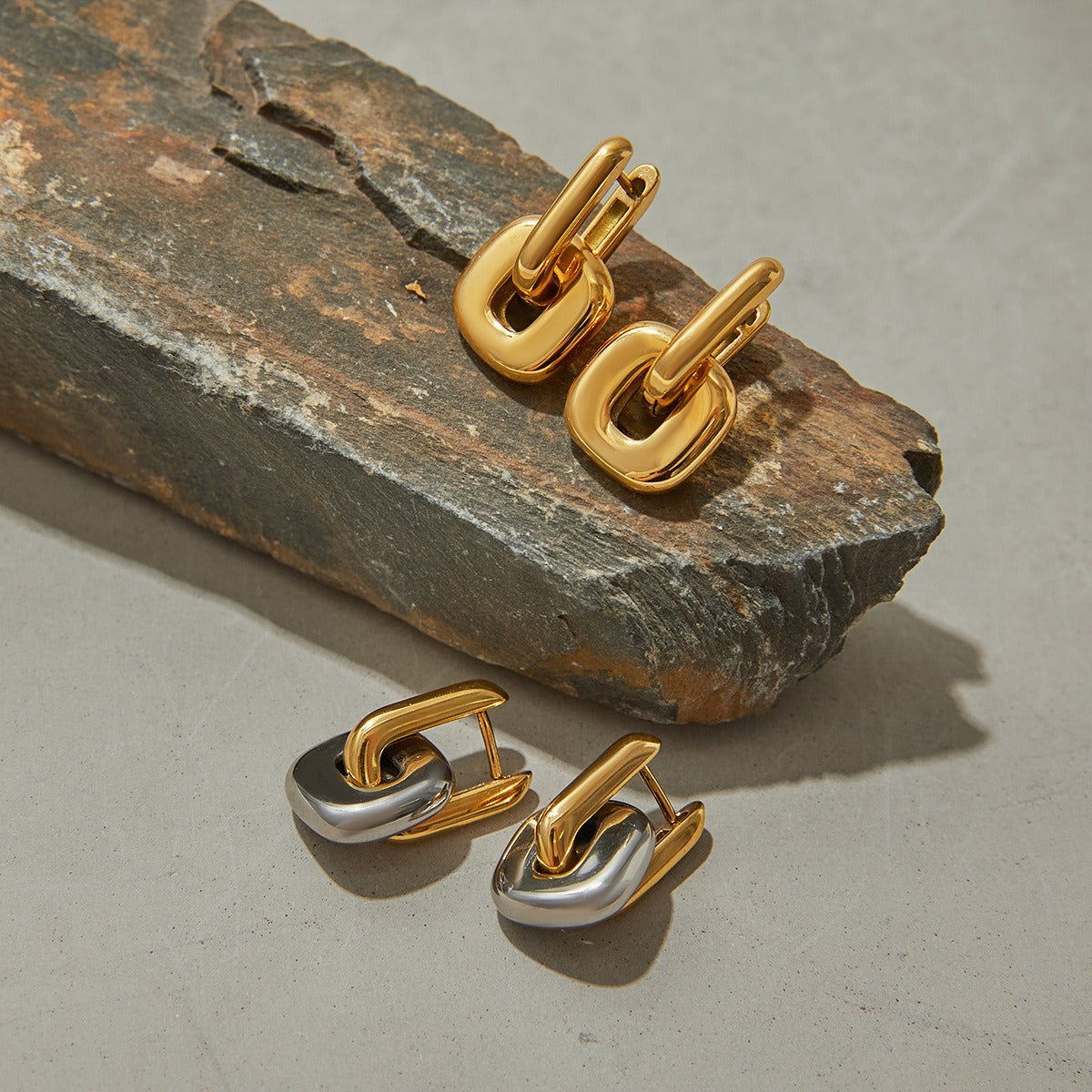 amethyst & sable axis frame earrings in mixed metal 18k gold and stainless steel on stone surface