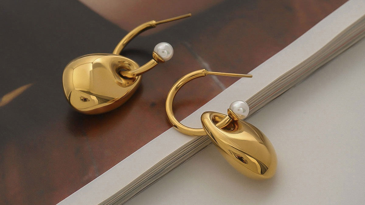Gold earrings with pearl accents on an open book