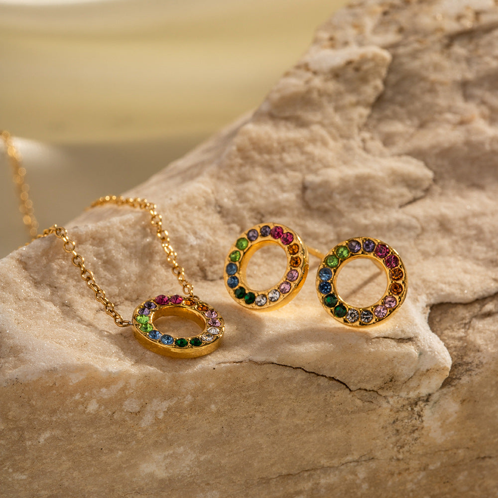 Gold jewelry set with colorful gemstones on a stone surface